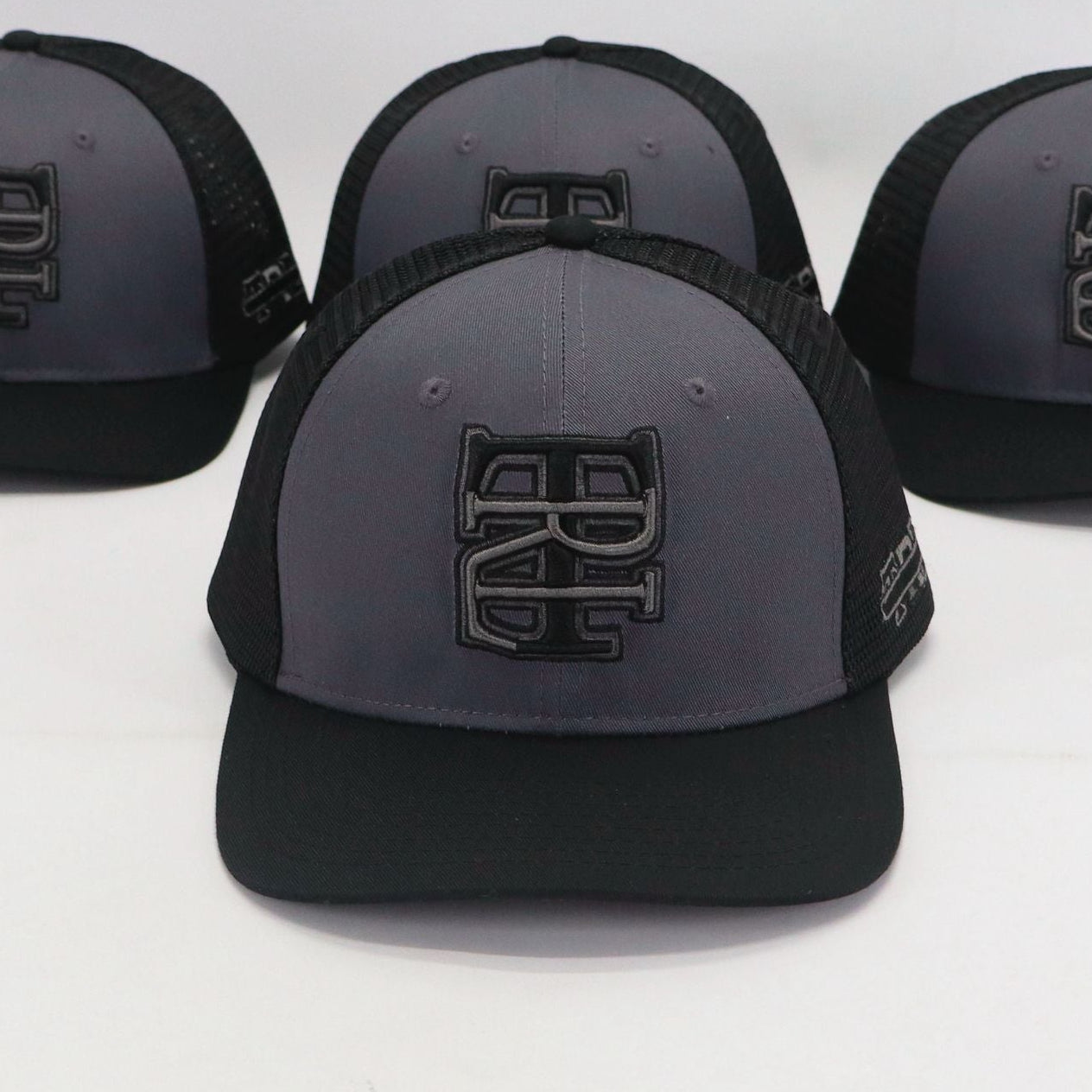 Four black and gray caps with a logo on a white background