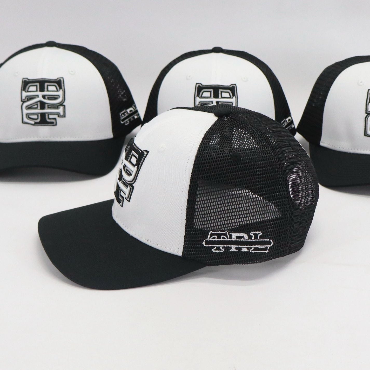 Four black and white caps with logos on a light gray background