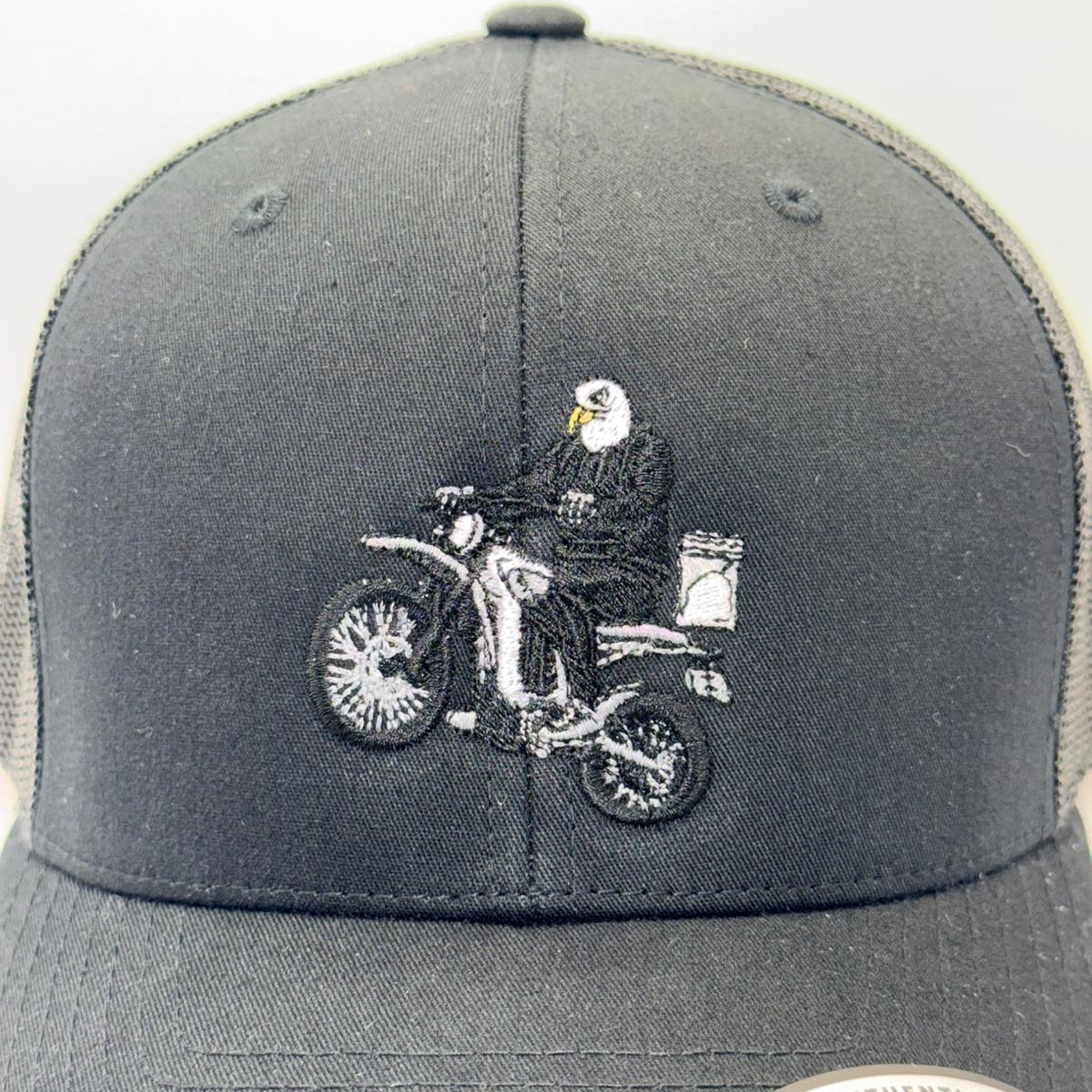 Gray snapback cap with embroidered design of a person on a motorcycle and an eagle.