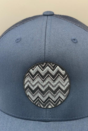 Blue cap with a black and white zigzag pattern on a beige background