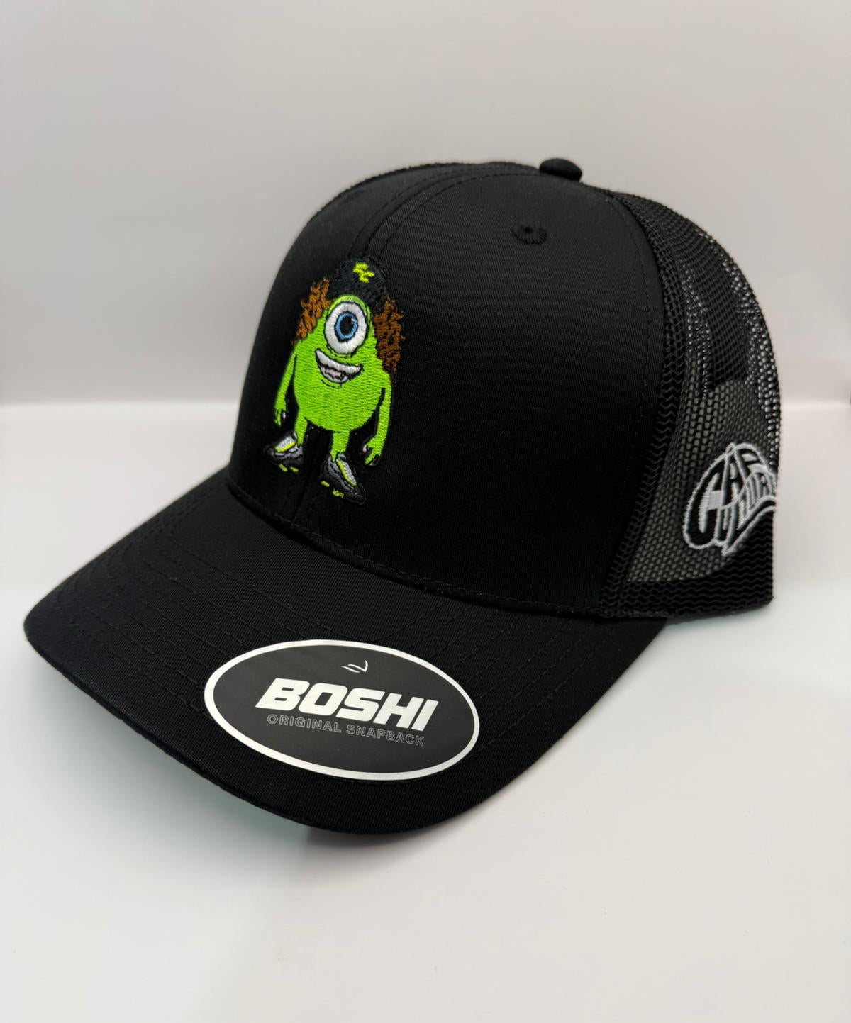 Black cap with green character design and 'Boshi' logo on a white background