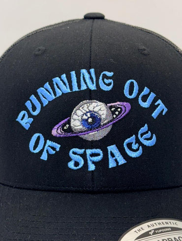 Black trucker cap with 'Running Out of Space' text and galaxy design on a white background
