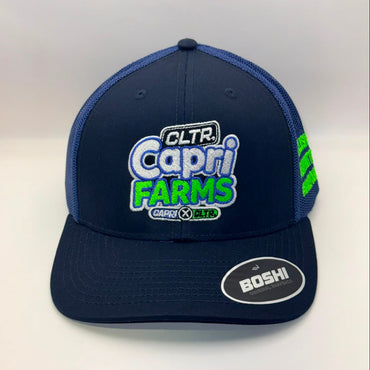 A navy blue trucker hat with a large embroidered front patch reading 'CLTR Capri Farms' in white, blue, and green. The cap has navy blue mesh side panels, a matching navy brim, and a visible 'BOSHI' sticker on the brim.