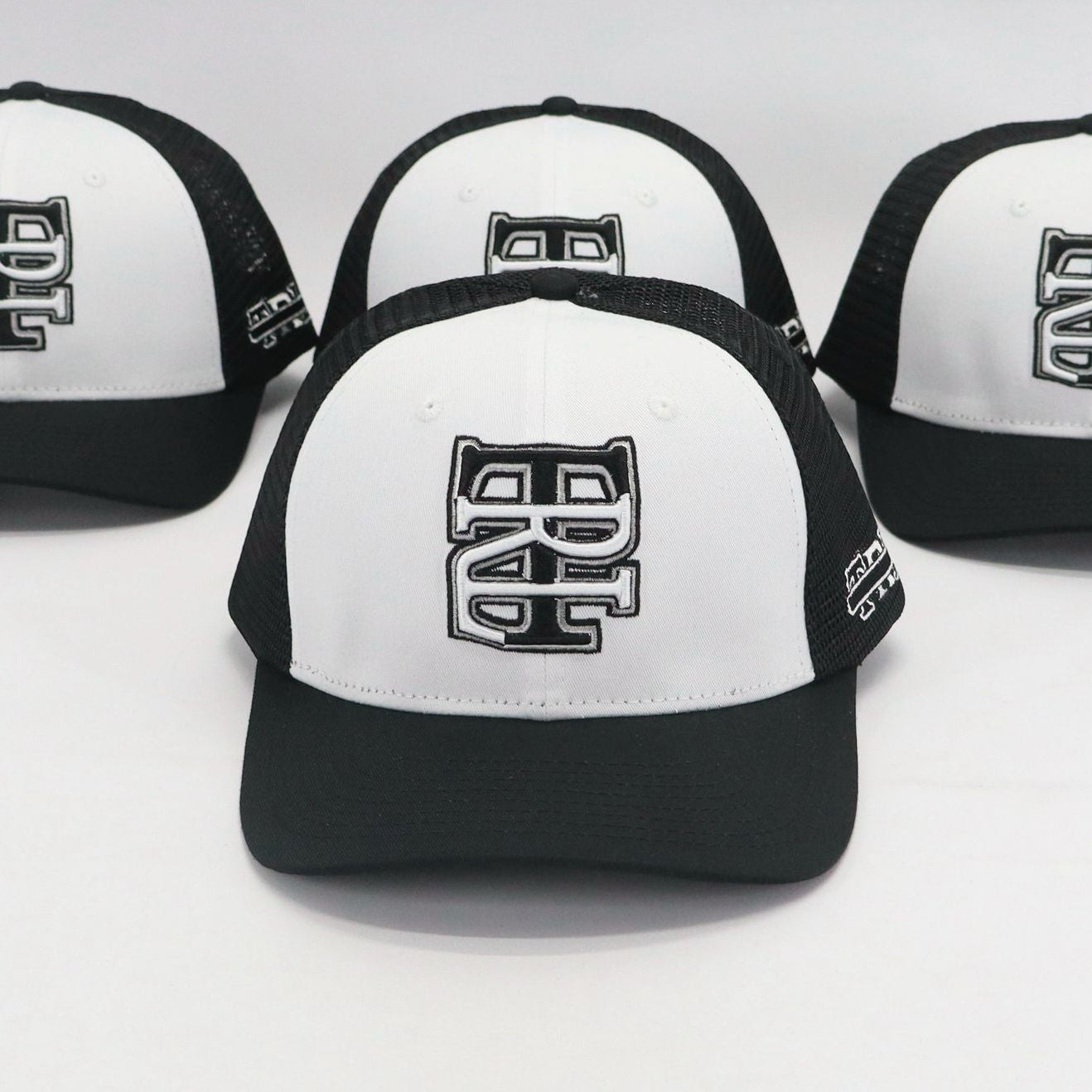 Four black and white caps with a logo on a light gray background
