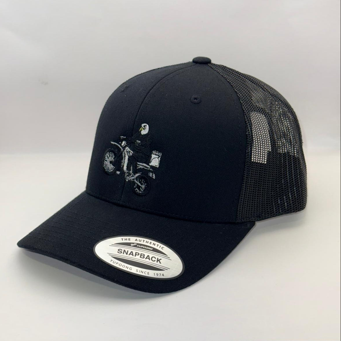 Black trucker cap with embroidered design on a white background