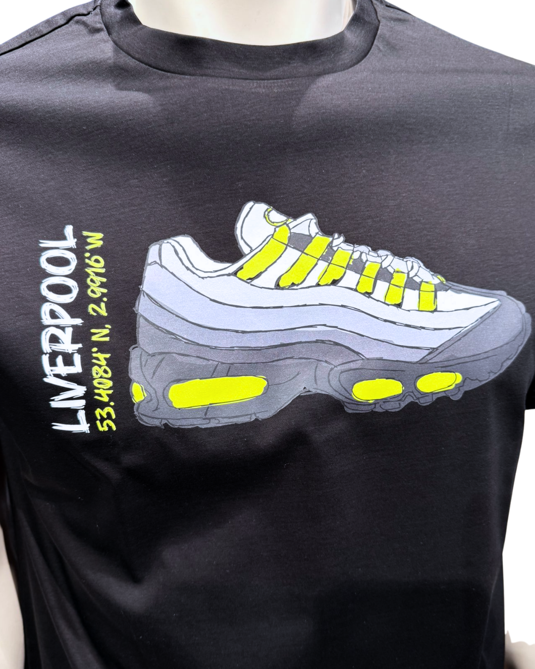 Black t-shirt with a graphic of a white sneaker with yellow accents and text on a white background