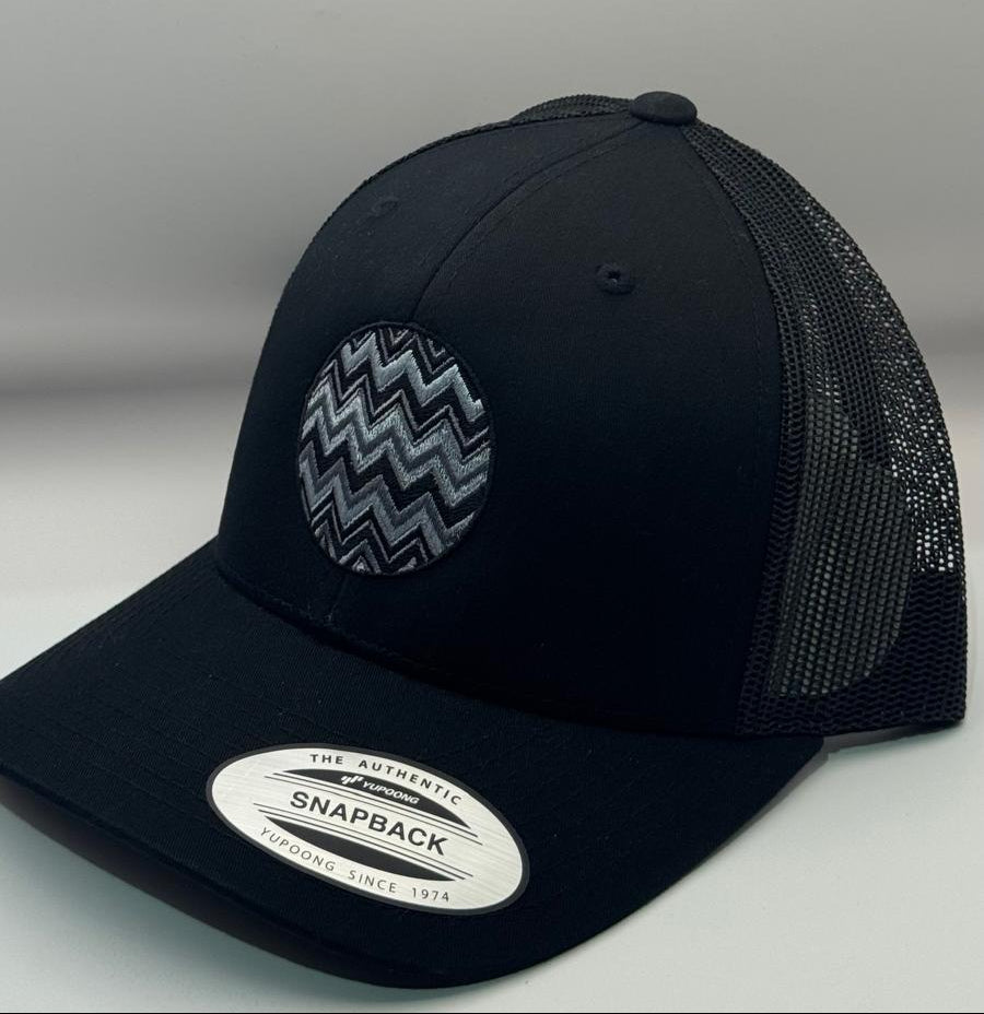 Black snapback cap with a zigzag pattern on a gray background