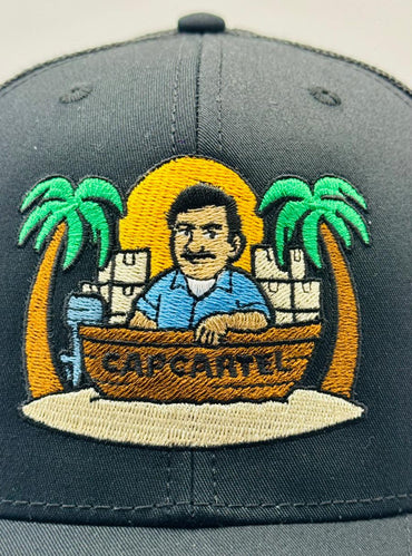 Gray cap with embroidered design of a man in a boat with palm trees and 'Cap Canel' text.