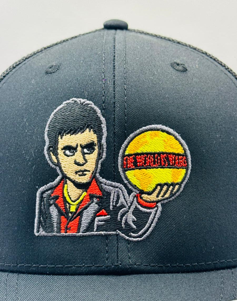 Gray cap with embroidered design of a character holding a ball on a gray background