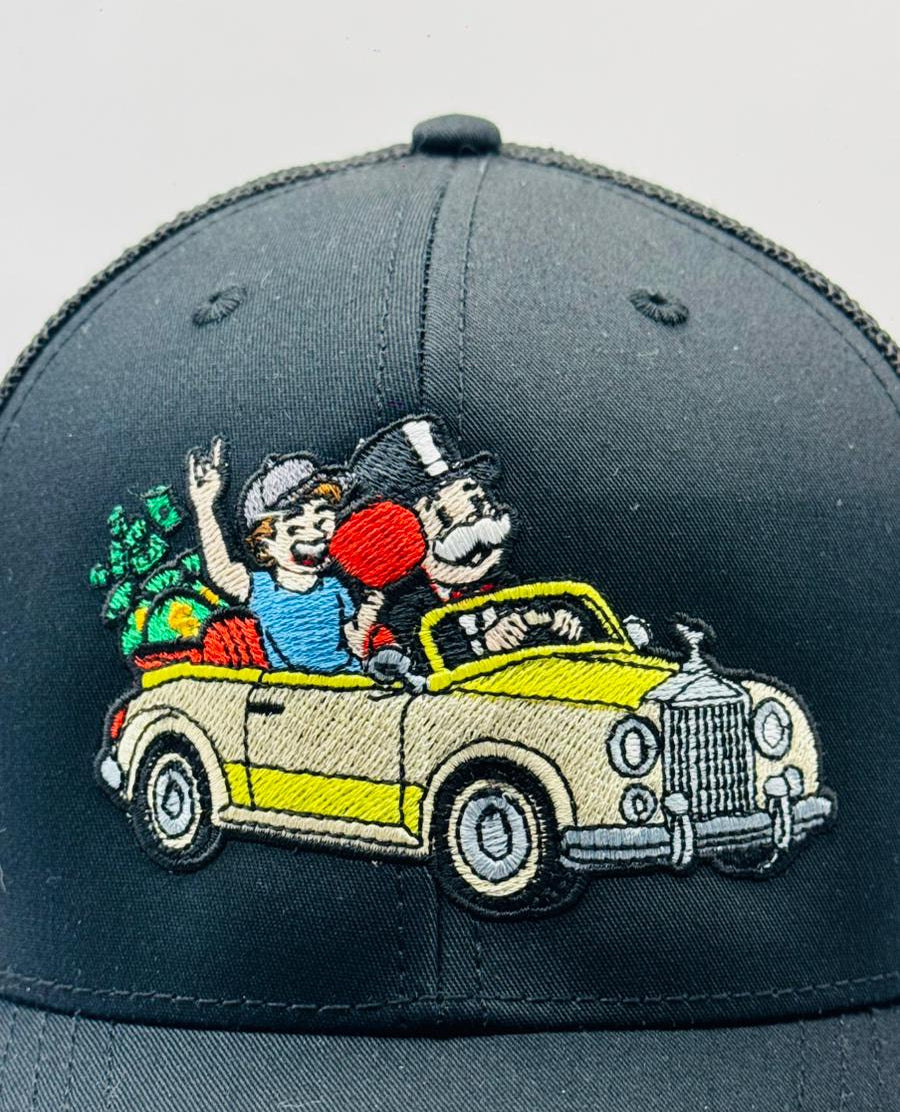 Gray cap with embroidered design of two cartoon characters in a vintage car on a white background