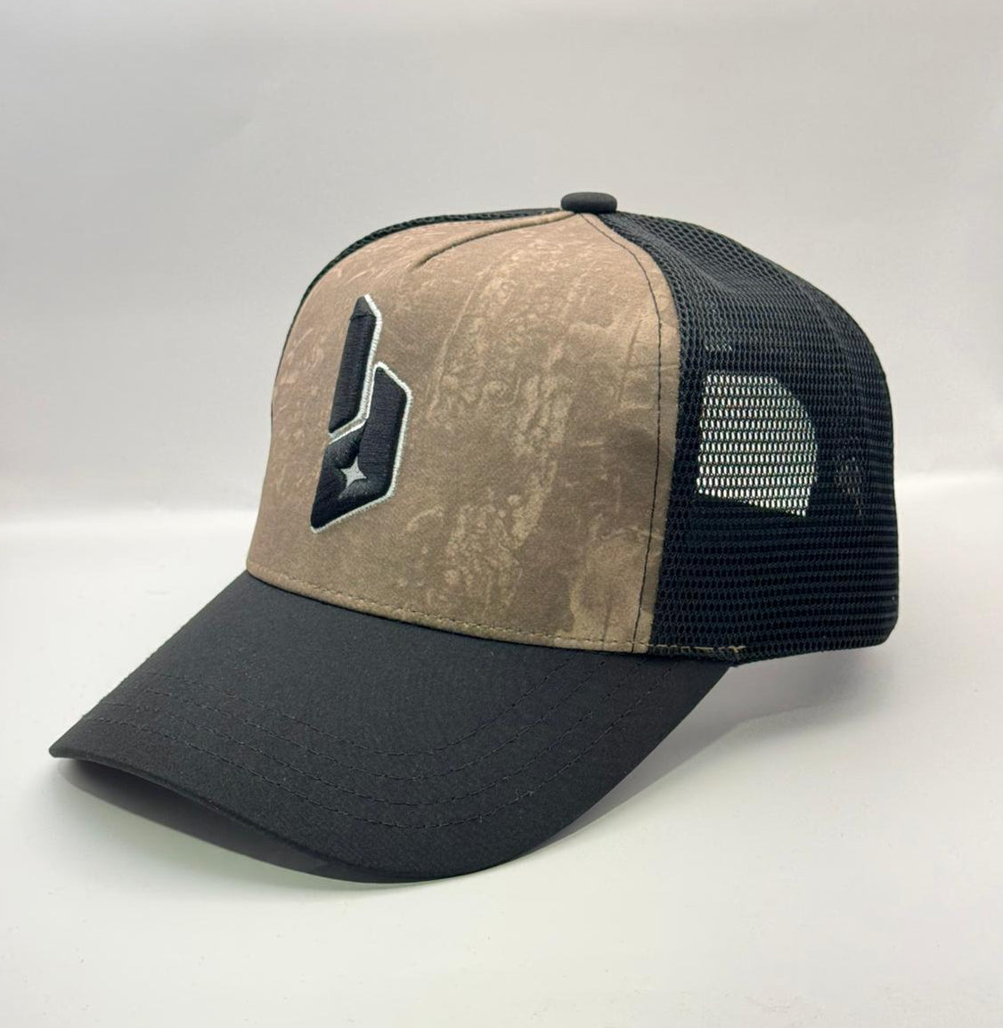 Beige and black cap with a logo on a white surface