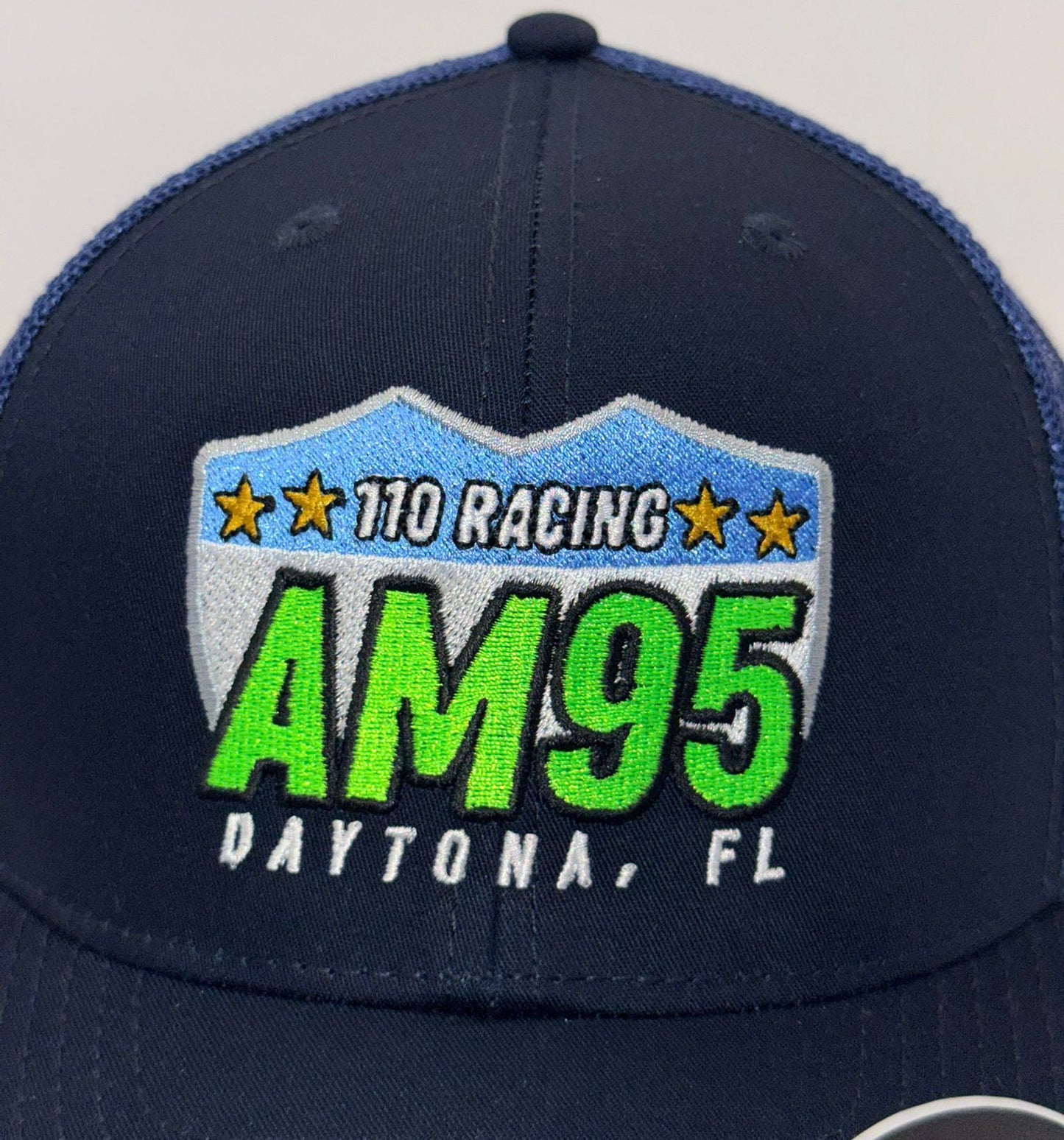 Navy blue cap with '110 Racing AM95 Daytona, FL' logo on a light gray background