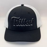 A black and white trucker hat with a black front panel, white mesh back, and a black embroidered 'Trilkest' logo on the front.