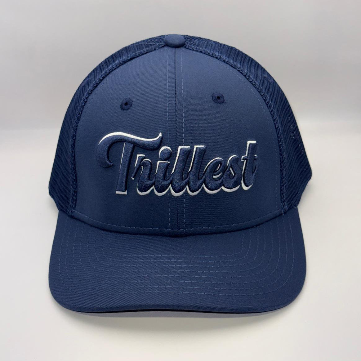 A navy blue trucker-style baseball cap with a curved brim and mesh back panels, featuring the word 'Trilfest' embroidered in metallic silver script across the front.