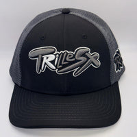 A black and gray trucker hat with a black front panel, gray mesh back, and a large stylized 'TRILEX' logo embroidered on the front.