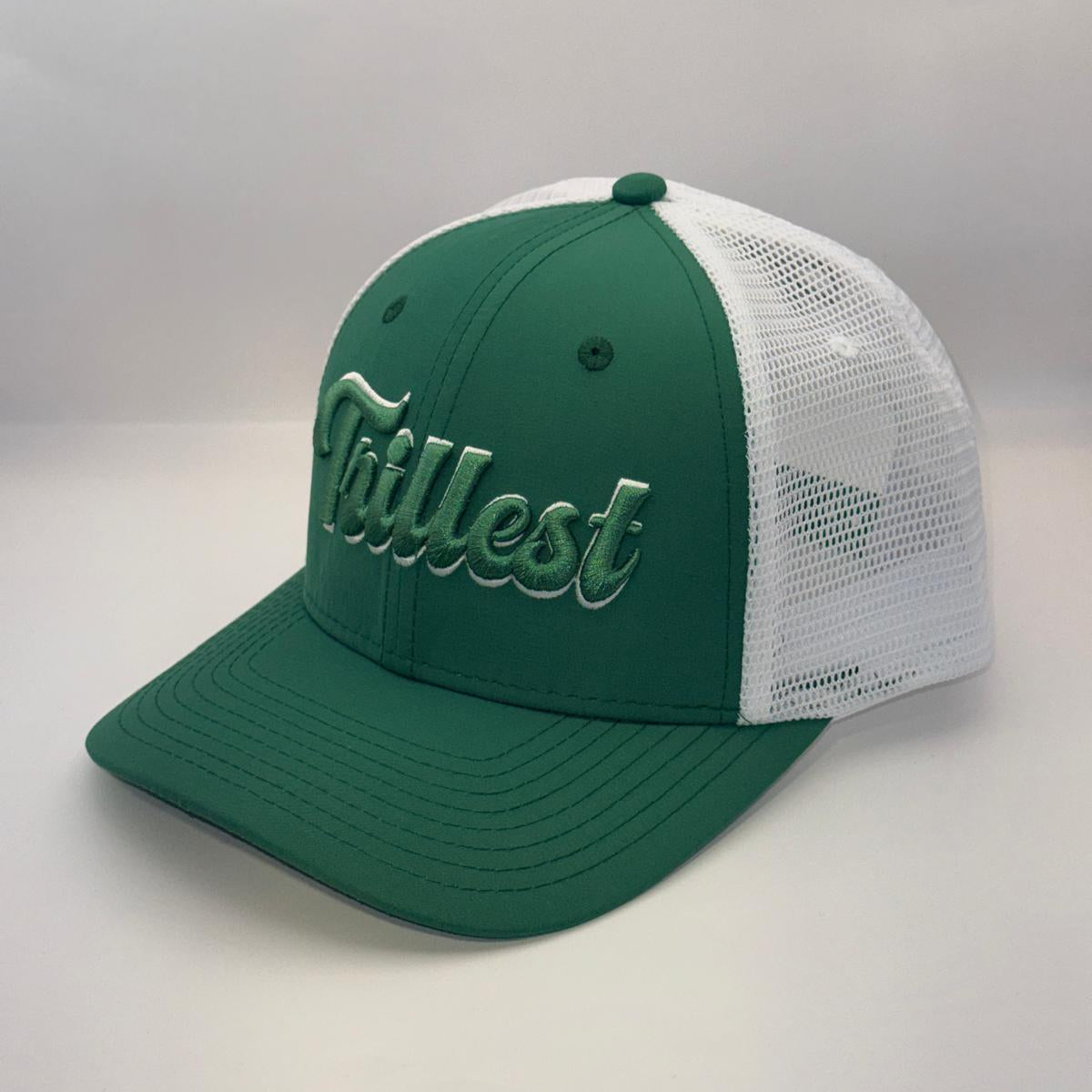 A green and white trucker-style baseball cap with 'Tittest' embroidered in white script across the front panels, set against a plain light gray background.