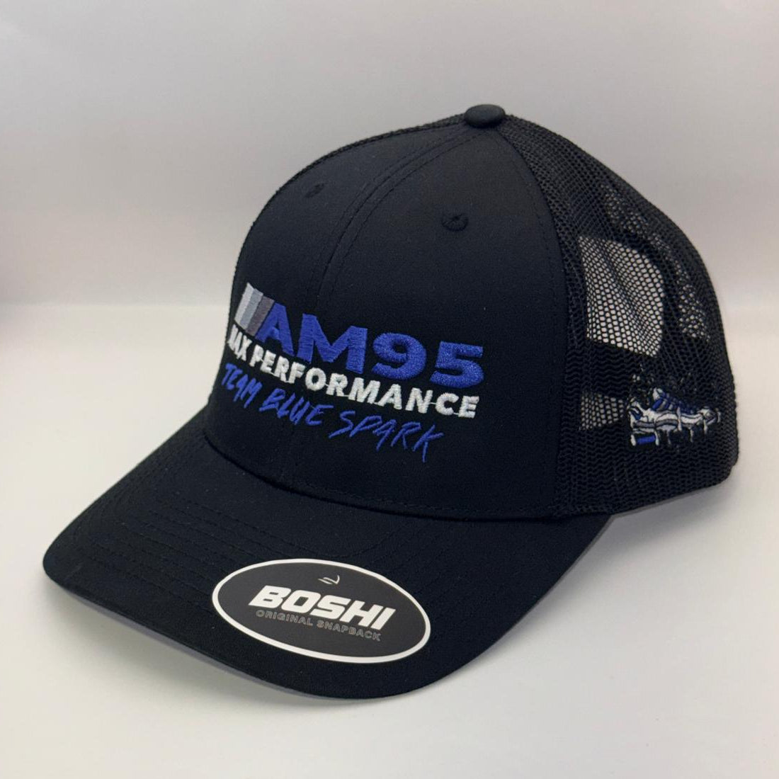 A black mesh-back trucker hat with a curved brim, featuring 'AM95 Racing Blue Spark' embroidered in blue and white on the front, and a circular white 'BOSHI' sticker on the brim.