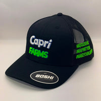 A black trucker-style baseball cap with embroidered 'Capri FARMS' text on the front in white and neon green, plus neon green hashtag-style text on the side mesh. A circular 'BOSHI' sticker is visible on the brim.