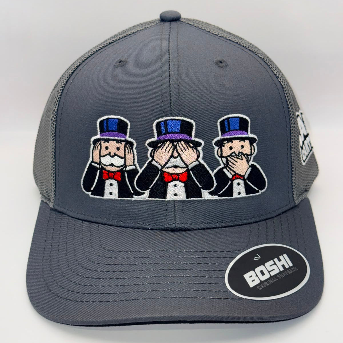 A dark gray trucker hat with a mesh back, featuring an embroidered patch of three Monopoly-style figures in black tuxedos and top hats on the front. A circular black and white 'BOSHI' sticker is on the brim.