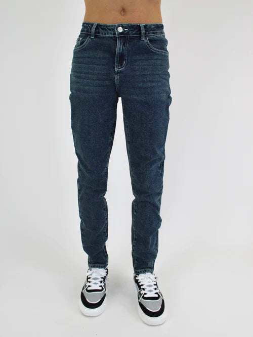 Person wearing blue jeans and black and white sneakers on a white background