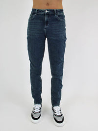 Person wearing blue jeans and black and white sneakers on a white background